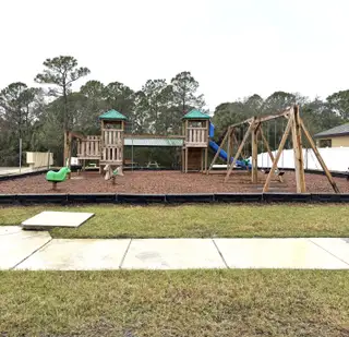 Charming community playground with wooden structures and slides in Adamson Creek by D.R. Horton (Cocoa, FL).