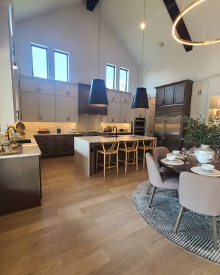 Spacious kitchen with vaulted ceiling, pendant lights, modern cabinetry, and dining area on a patterned rug.