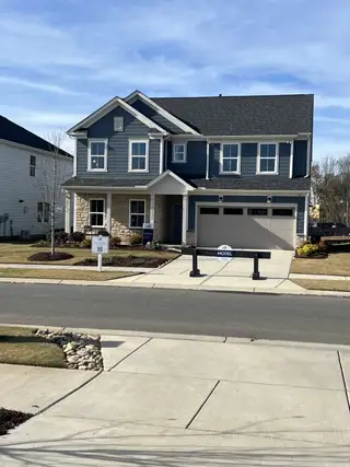 Street view A charming blue and stone facade home in Parkside Crossing by Pulte Homes, Charlotte, NC, with manicured landscaping.