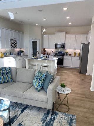 Model Home A modern kitchen-living space featuring white cabinetry, stainless steel appliances, and sleek decor.