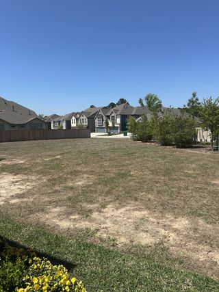 Street view Wide open lot with nearby homes under clear blue skies in Woodforest by Chesmar Homes, Montgomery, TX.