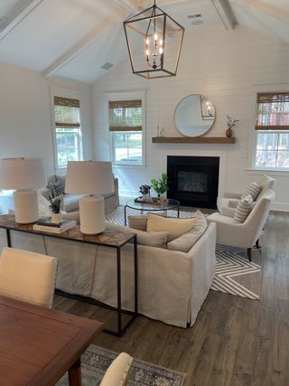 A cozy living room with a vaulted ceiling, elegant chandelier, fireplace, and neutral-toned furnishings.