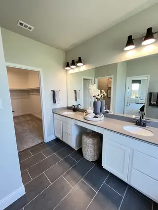 A modern bathroom featuring dual sinks, elegant lighting, and sleek gray tile flooring.