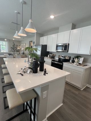 A modern kitchen with sleek white cabinets, pendant lights, and a spacious island with bar seating.