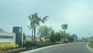 A lushly landscaped entrance at Towns at Woodsdale Villas by D.R. Horton in Wesley Chapel, FL, featuring vibrant greenery.