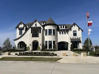 A grand stone façade home with elegant landscaping in Silverleaf Estates by Grand Homes, Frisco, TX.