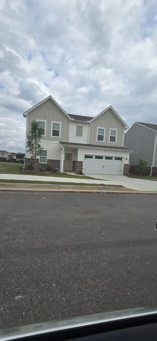 Street view A charming two-story home with a modern facade and landscaped yard in Ashford Park by Starlight Homes (Covington, GA).