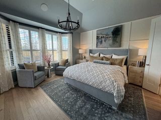 Model Home A cozy bedroom with elegant bay windows, stylish gray seating, and contemporary decor.