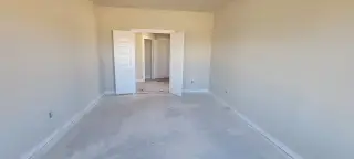 A spacious, unfinished room with double doors, neutral walls, and ample natural light.