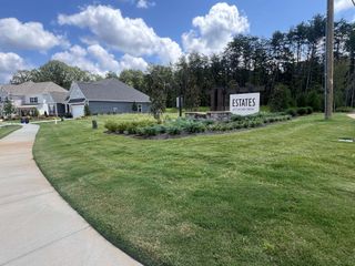 A beautifully landscaped entrance at Estates at Sugar Creek by Taylor Morrison in Indian Land, SC, featuring lush greenery.