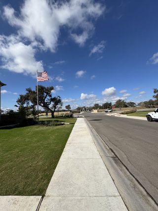 Street view A serene street view adorned with an American flag in Parmer Ranch 60′ by Sitterle Homes (Georgetown, TX).