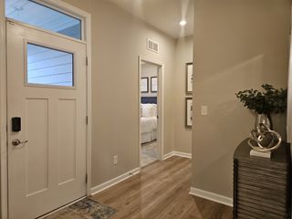 A welcoming entryway featuring a modern console table, decorative accents, and warm wood flooring leading into a cozy bedroom.