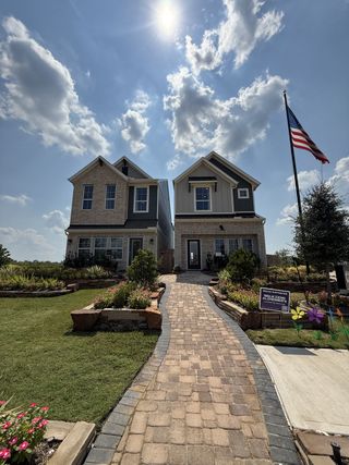 Twin modern homes with charming brick, landscaped paths in Sienna by Chesmar Homes (Missouri City, TX).