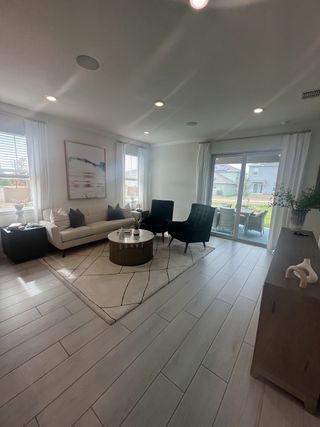 Model Home A bright living room with sleek flooring, cozy seating, and large windows offering plenty of natural light.