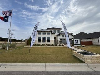 Street view Beautiful modern home with stone accents and landscaped lawn in Heights at San Gabriel by GFO Home (Georgetown, TX).