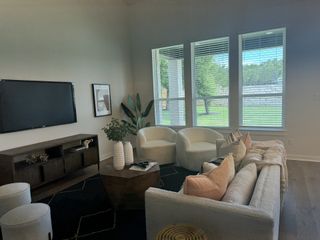 Model Home A stylish family room with a mounted TV, plush seating, and natural elements, perfect for relaxing and entertaining.