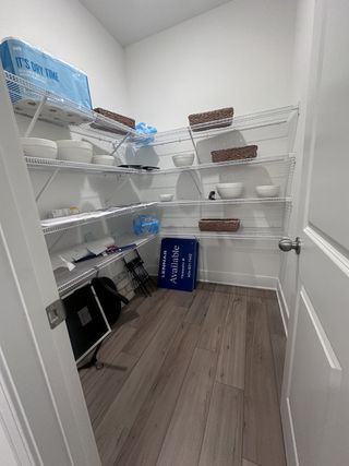 A spacious pantry with wooden flooring, white shelving, and organized storage baskets.