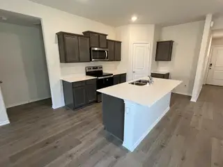 A spacious kitchen with dark wood cabinetry, a large center island, and stainless steel appliances.
