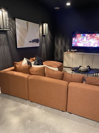 Model Home A cozy media room with a plush brown sectional, modern wall art, and soft lighting.