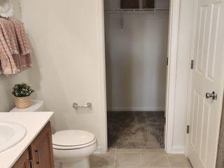 Model Home Modern bathroom featuring soft pink towels, sleek fixtures, and a cozy walk-in closet.