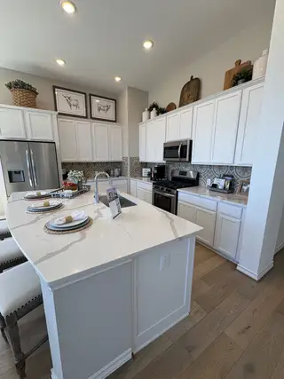 A modern kitchen featuring sleek white cabinetry, marble countertops, and stylish decor accents.