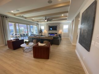 Stylish living area with wood floors, beamed ceiling, plush seating, stone fireplace, and large sliding glass doors to patio.