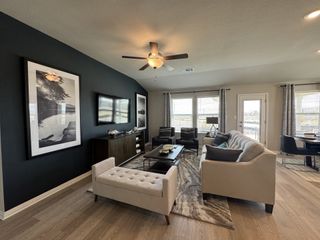 A cozy living room featuring a dark accent wall, elegant seating, and large windows for natural light.