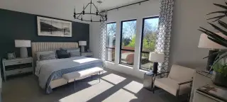 Elegant master suite with a tufted bed, chic lighting, and large windows showcasing outdoor greenery.