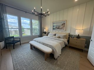 A serene bedroom with large windows, cozy bedding, and a chic chandelier, featuring peaceful decor and soft lighting.