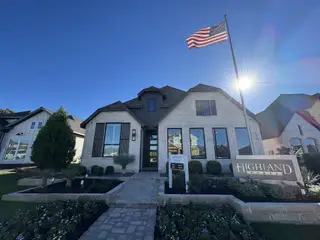 Model Home A beautiful white brick home with modern black accents and lush landscaping in 6 Creeks at Waterridge by Highland Homes (Kyle, TX).