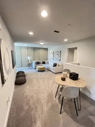 Model Home A cozy recreation room with modern artwork, plush carpet, and a comfy sectional, perfect for relaxation and gatherings.