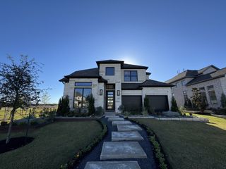 Street view A modern stone facade home with lush landscaping in Santa Rita Ranch by Perry Homes (Liberty Hill, TX).