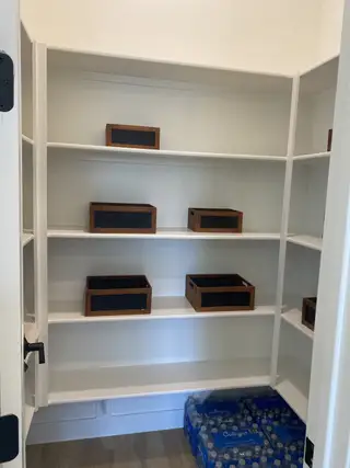 A spacious pantry with white shelving, wooden baskets, and flooring. Perfect for organized storage and convenience.