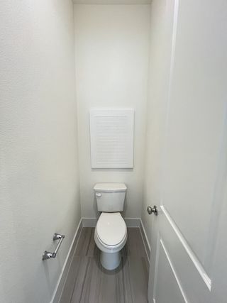 A compact powder room featuring gray floor tiles, a sleek white toilet, and minimalist design.