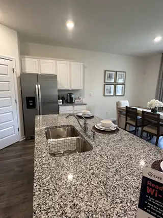 A modern kitchen with granite countertops, stainless steel appliances, and a dining area with elegant wall art.