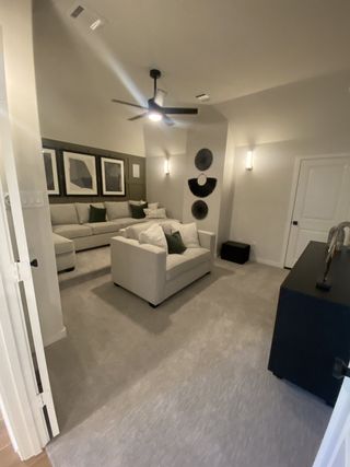 Model Home A cozy living room with plush sofas, modern art, a ceiling fan, and soft lighting for a tranquil ambiance.