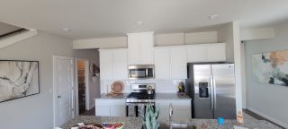 A modern kitchen with granite countertops, sleek white cabinets, and stainless steel appliances.