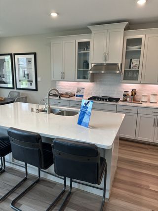 A modern kitchen with sleek white cabinetry, spacious island, and stylish barstools.