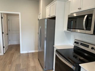 A sleek kitchen featuring stainless steel appliances, white cabinetry, and light wood flooring.
