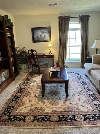 Cozy living room with a patterned rug, elegant wooden furniture, and soft lighting.