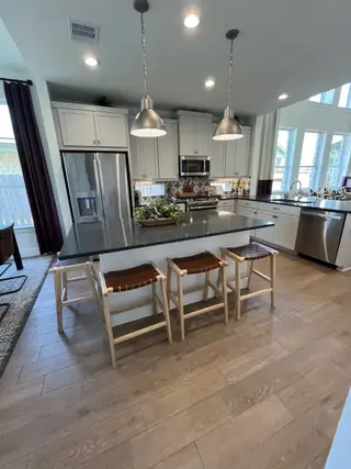 A stylish kitchen with stainless steel appliances, pendant lighting, and a spacious island with wooden stools.