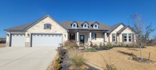 Street view A charming stone exterior home with dormer windows in Jordan's Ranch by First America Homes (San Antonio, TX).