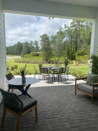 A charming patio with wicker furniture overlooking a lush, landscaped garden and serene greenery.