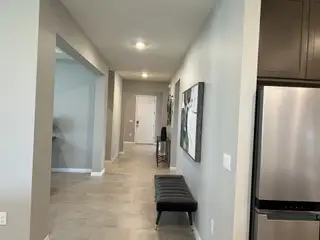 Model Home A spacious hallway with modern lighting, elegant tile flooring, and stylish decor leading to the main living areas.