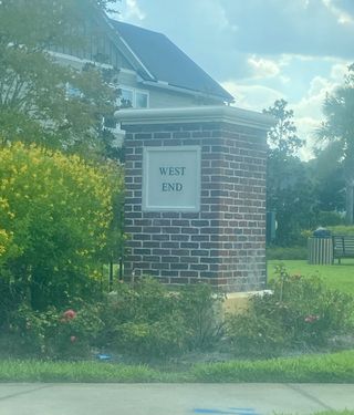 A brick entrance sign with lush greenery in West End at Town Center by ICI Homes (Ponte Vedra, FL).