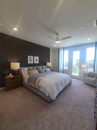 A cozy bedroom featuring a plush bed, modern accent wall, ample natural light, and elegant furnishings.