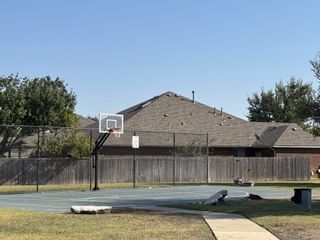 Community Amenities A well-maintained basketball court with a sturdy hoop, set against a backdrop of suburban homes in Blackhawk by GFO Home (Pflugerville, TX).