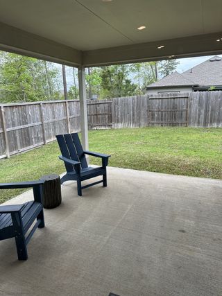 Model Home A cozy covered patio with blue Adirondack chairs and a private fenced backyard, perfect for relaxation.