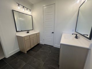 A modern bathroom featuring dual vanities, sleek black fixtures, and elegant lighting above large mirrors.