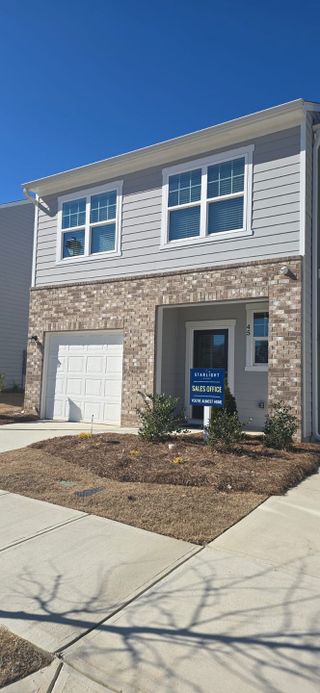 A two-story townhome with brick and gray siding, marked as a "Sales Office" for Starlight Homes.